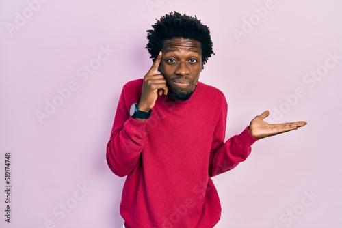 Young african american man wearing casual clothes confused and annoyed with open palm showing copy space and pointing finger to forehead. think about it.