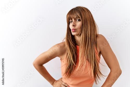 Hispanic woman with bang hairstyle standing over isolated background looking at the camera blowing a kiss on air being lovely and sexy. love expression.