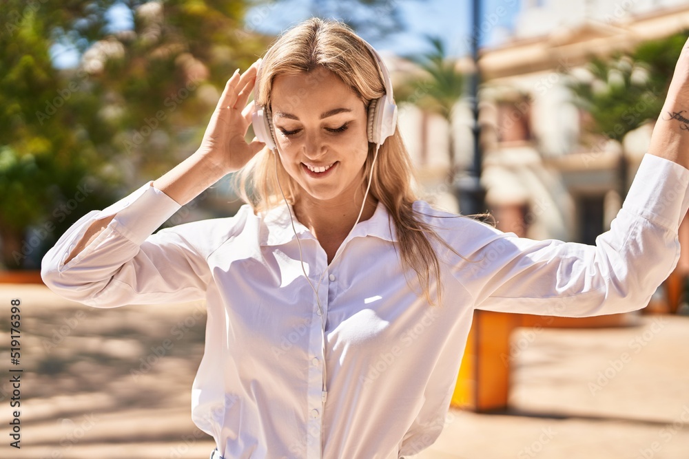 Young blonde woman smiling confident listening to music and dancing at park