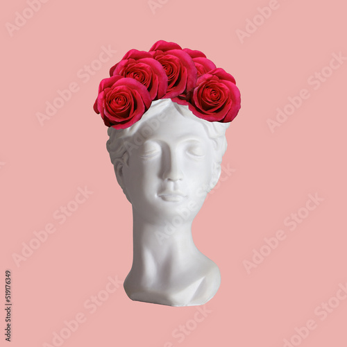 Female antique statue's bust with rim of red flowers roses on her head isolated on a pink color background. Trendy collage in magazine surreal style. 3d contemporary art. Modern design 