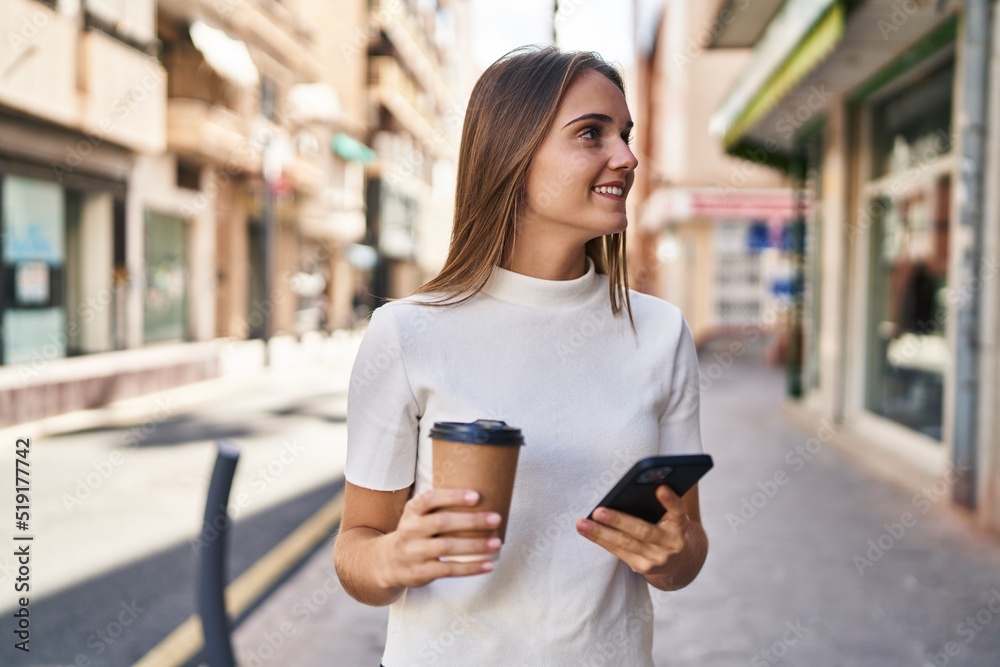 Young blonde woman using smartphone and drinking coffee at street Young blonde woman using smartphone and drinking coffee at street