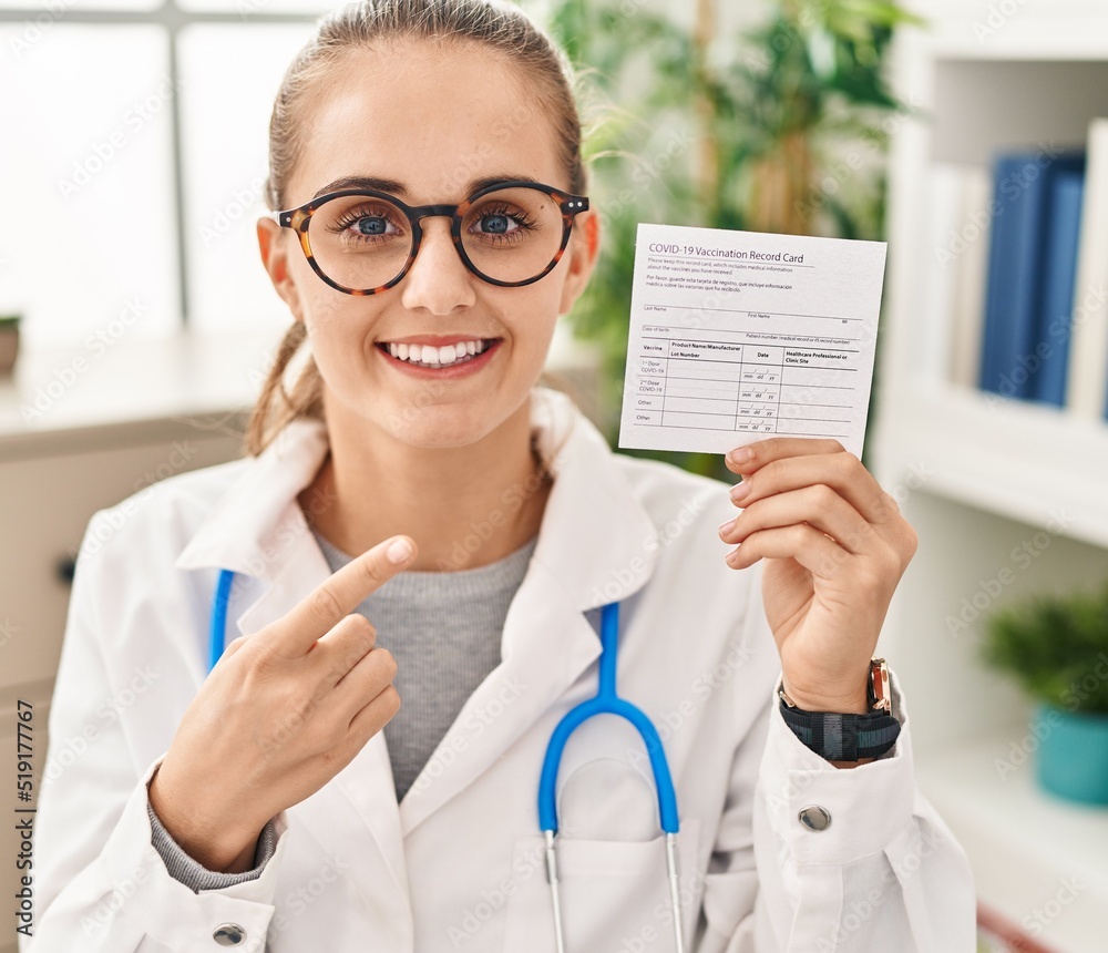 Young doctor woman holding covid certificate smiling happy pointing with hand and finger