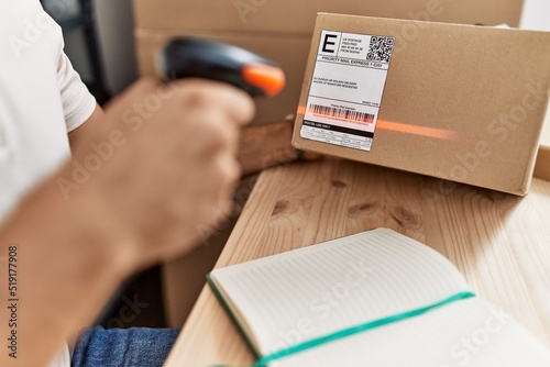 Young hispanic man scanning package label with barcode reader at storehouse