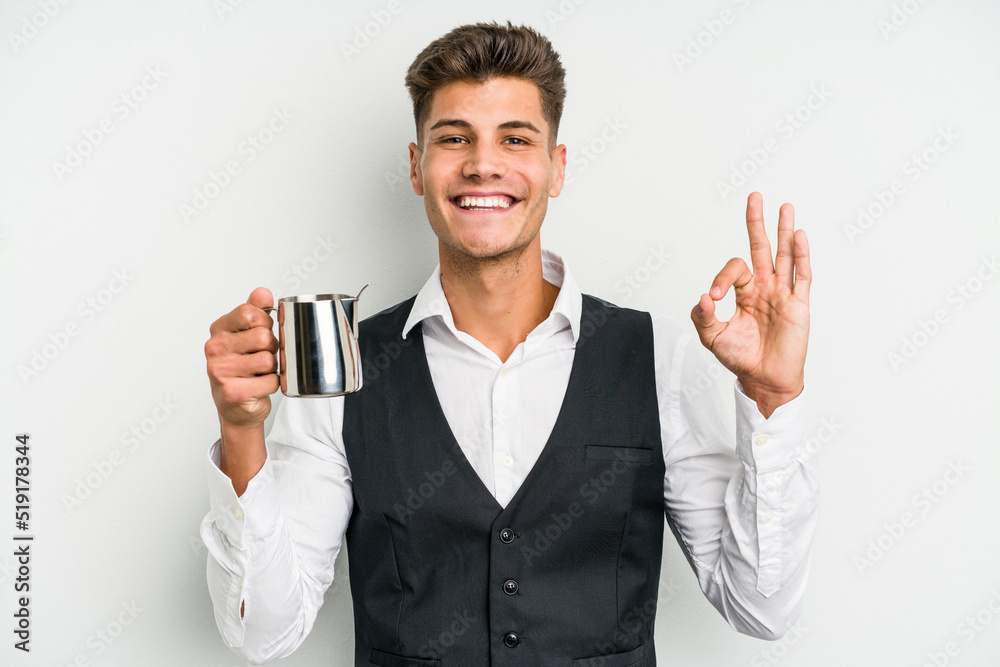 Young caucasian barista man isolated on yellow background cheerful and confident showing ok gesture.