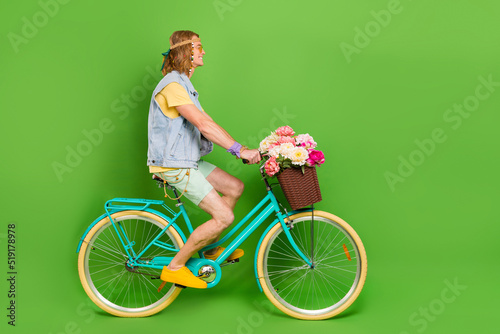 Fototapeta Naklejka Na Ścianę i Meble -  Full size profile photo of handsome hippy guy driving bike look empty space isolated on green color background