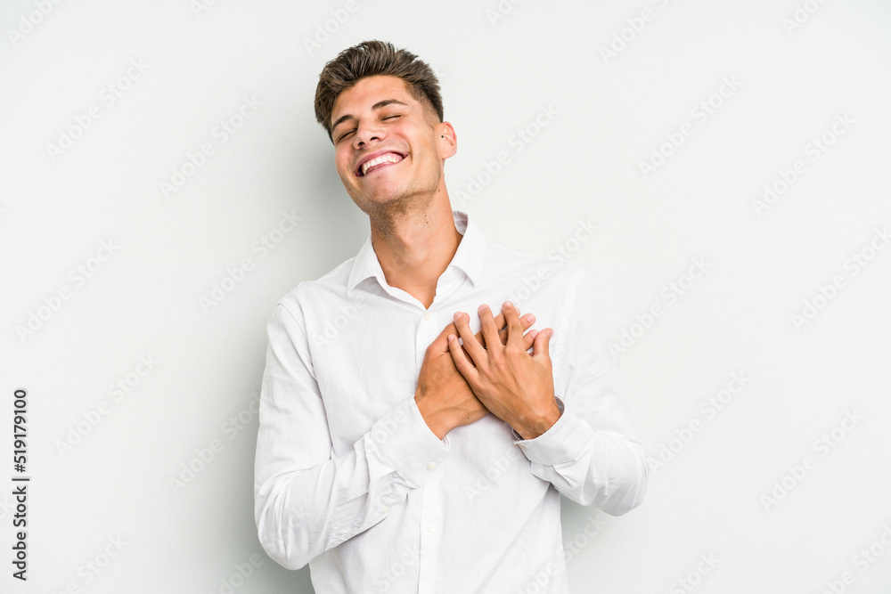 Young caucasian man isolated on white background laughing keeping hands on heart, concept of happiness. Young caucasian man isolated on white background laughing keeping hands on heart, concept of happiness.