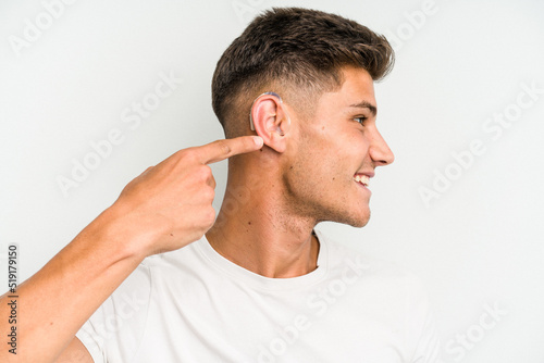 Young caucasian man wearing a hearing aid isolated on white background