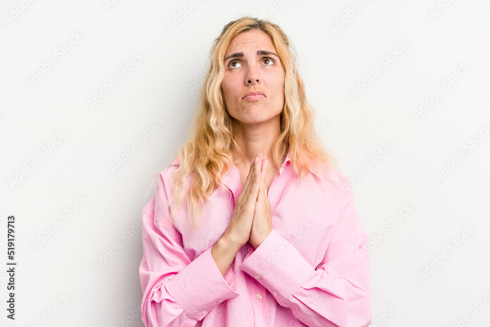 Young caucasian woman isolated on white background holding hands in pray near mouth, feels confident. Young caucasian woman isolated on white background holding hands in pray near mouth, feels confident.