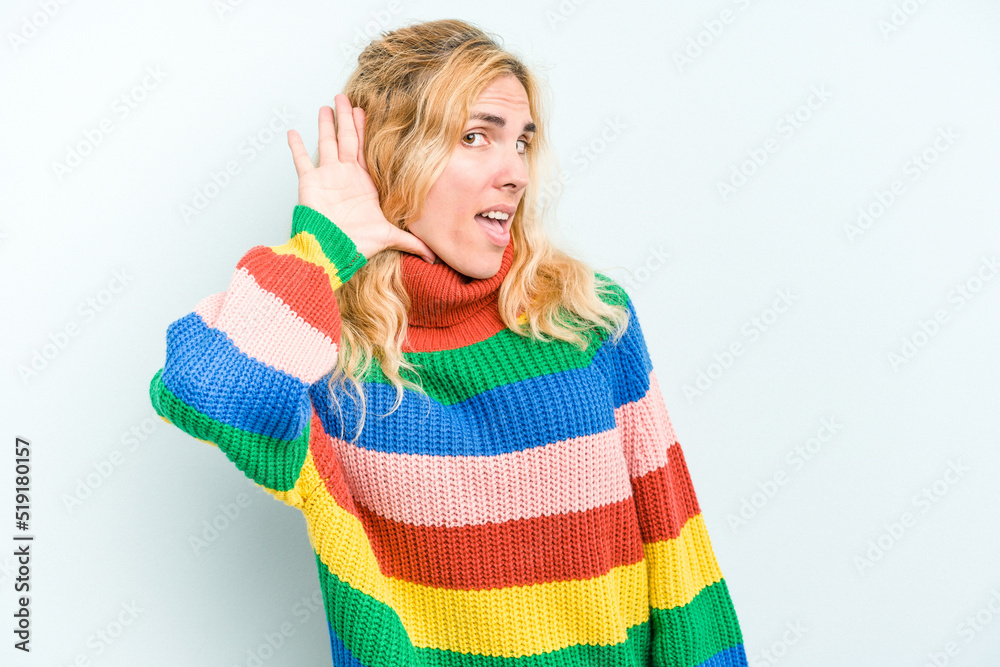 Young caucasian woman isolated on blue background trying to listening a gossip. Young caucasian woman isolated on blue background trying to listening a gossip.