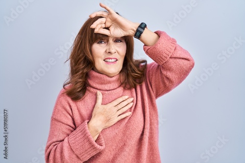 Middle age hispanic woman standing over isolated background touching forehead for illness and fever, flu and cold, virus sick