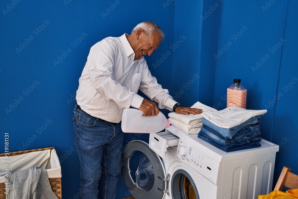 Senior man smiling confident pouring detergent on washing machine at laundry room Senior man smiling confident pouring detergent on washing machine at laundry room