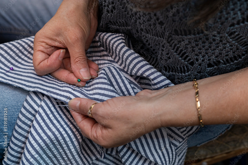 Latin American seamstress hands inserting a pin into a garment.