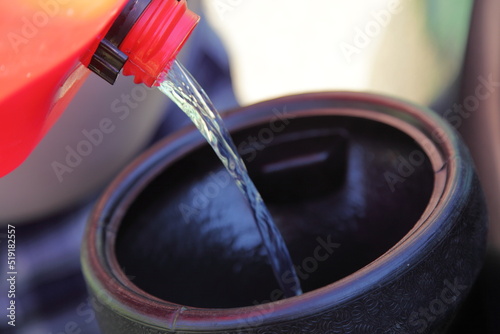 Gasoline transfusion from a plastic gas tank through a plastic funnel. Danger of ignition of fuel from static electricity during pouring. Safety of refueling