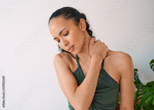 A young multi-ethnic woman holds her neck in pain during yoga