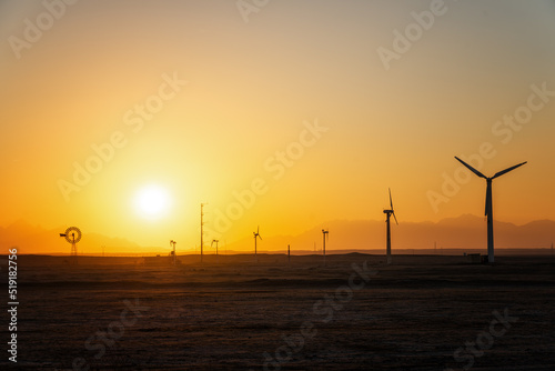 Wind power plants in desert at sunset
