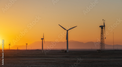 Wind power plants in desert at sunset