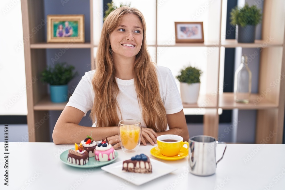 Young caucasian woman eating pastries t for breakfast looking away to side with smile on face, natural expression. laughing confident. Young caucasian woman eating pastries t for breakfast looking away to side with smile on face, natural expression. laughing confident.