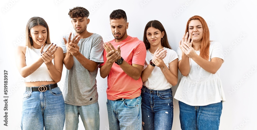 Group of young friends standing together over isolated background suffering pain on hands and fingers, arthritis inflammation Group of young friends standing together over isolated background suffering pain on hands and fingers, arthritis inflammation