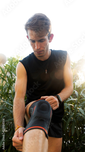man putting on the knee brace to play sports photo