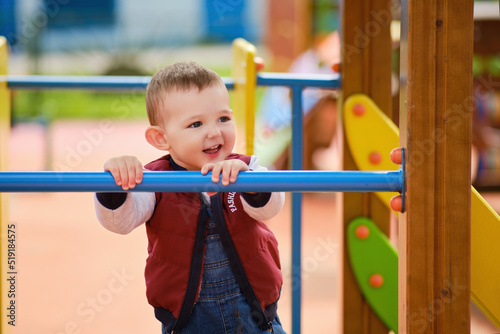 Happy toddler baby boy on the playground, smiling child aged one year