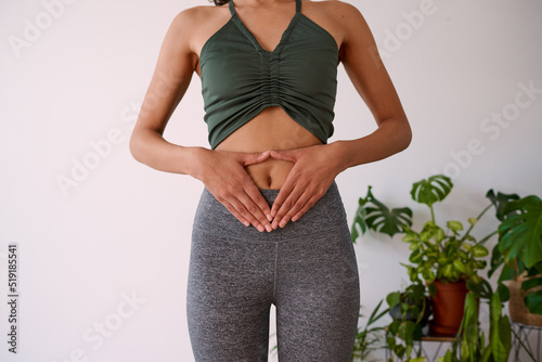 A young multi-ethnic woman holds her hands to her stomach, illustrate gut health