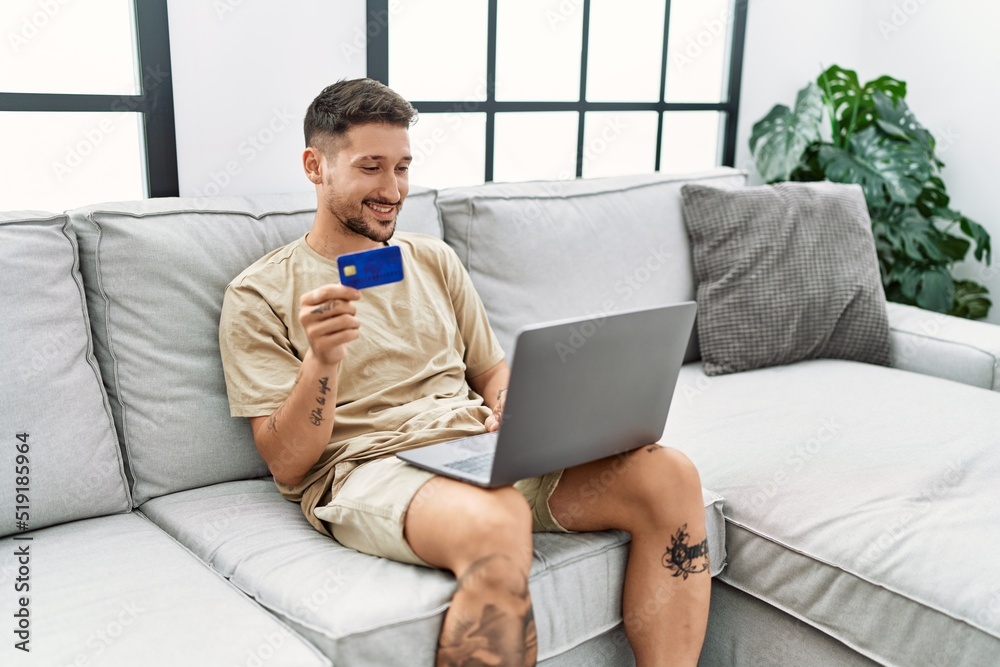 Young hispanic man using laptop and credit card at home Young hispanic man using laptop and credit card at home