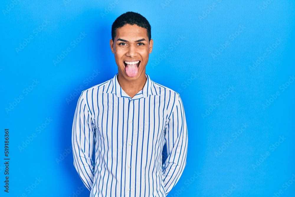 Young african american guy wearing casual clothes sticking tongue out happy with funny expression. emotion concept. Young african american guy wearing casual clothes sticking tongue out happy with funny expression. emotion concept.