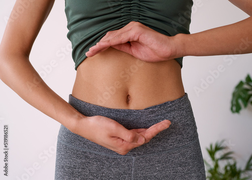 Close up of a young multi-ethnic woman's stomach cupped by her hands photo