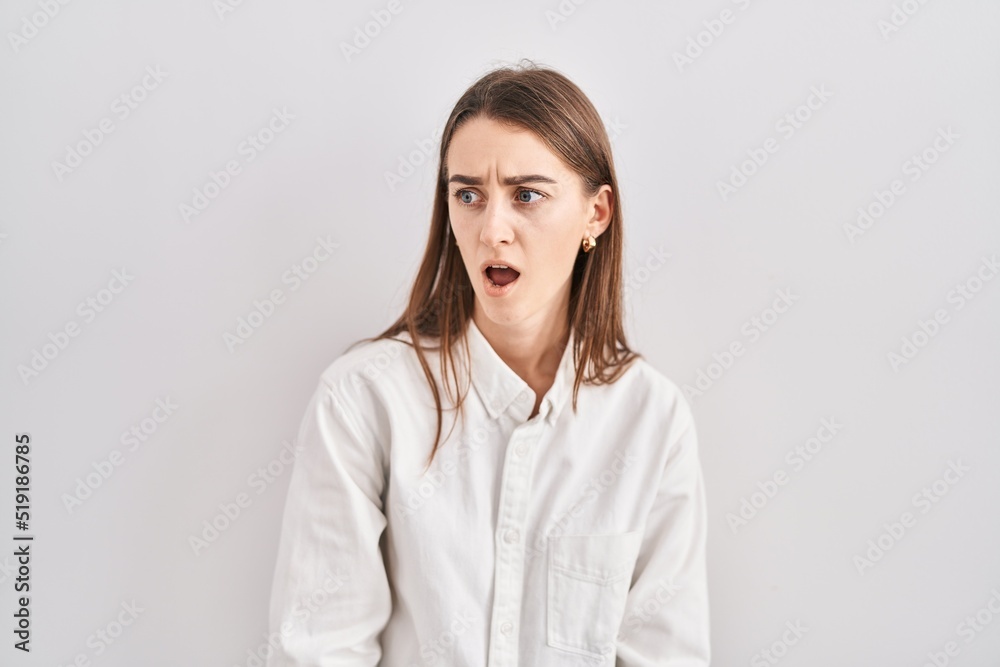 Young caucasian woman standing over isolated background in shock face, looking skeptical and sarcastic, surprised with open mouth Young caucasian woman standing over isolated background in shock face, looking skeptical and sarcastic, surprised with open mouth