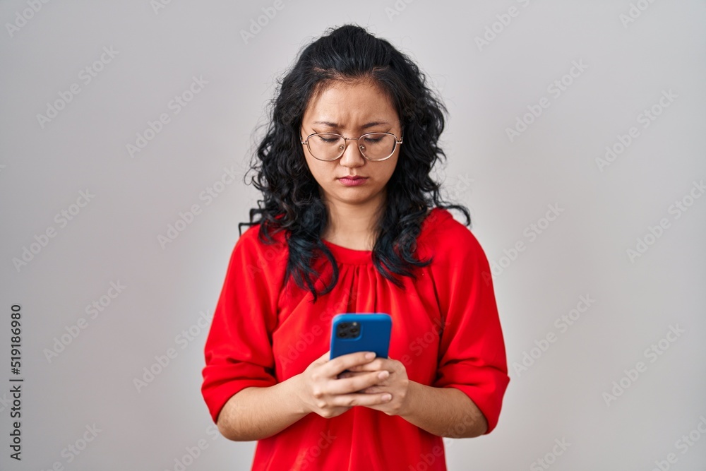 Young asian woman using smartphone typing message skeptic and nervous, frowning upset because of problem. negative person. Young asian woman using smartphone typing message skeptic and nervous, frowning upset because of problem. negative person.
