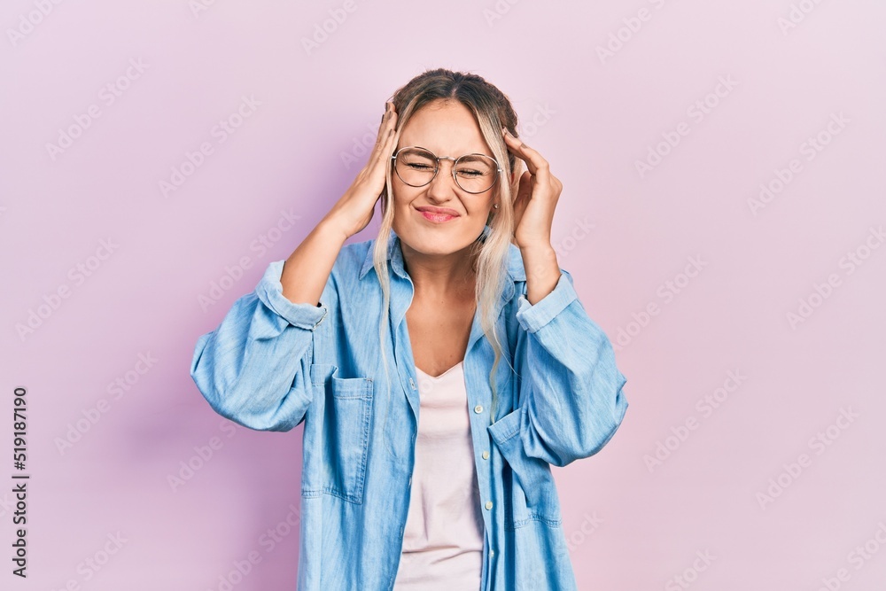 Beautiful young blonde woman wearing casual clothes and glasses suffering from headache desperate and stressed because pain and migraine. hands on head. Beautiful young blonde woman wearing casual clothes and glasses suffering from headache desperate and stressed because pain and migraine. hands on head.