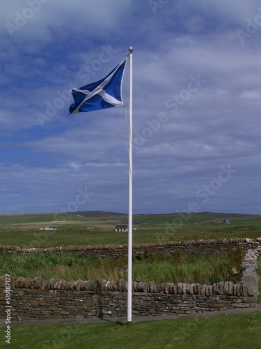 The Scottish flag flies over the Stone Age archaeological site of Skara Brae, Orkney Mainland, Orkney Islands, Scotland, United Kingdom