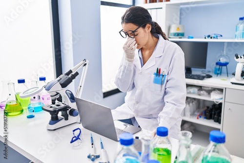 Young hispanic woman wearing scientist uniform stressing working at laboratory