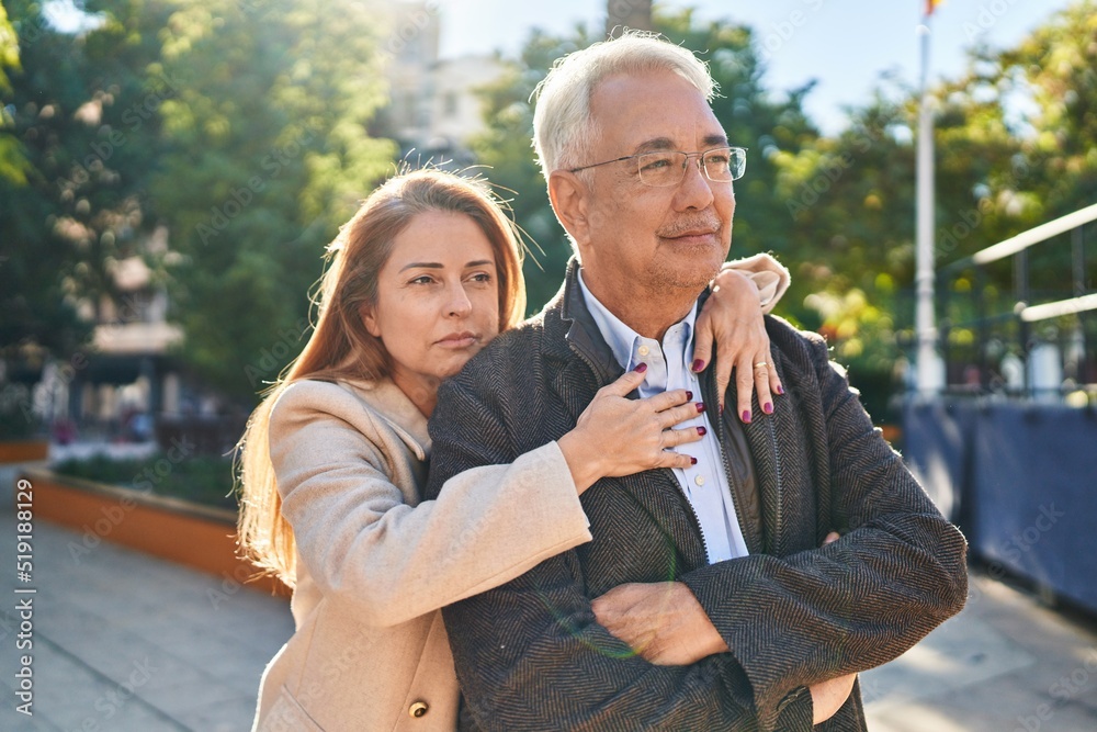 Fototapeta premium Middle age man and woman couple hugging each other standing with relaxed expression at park