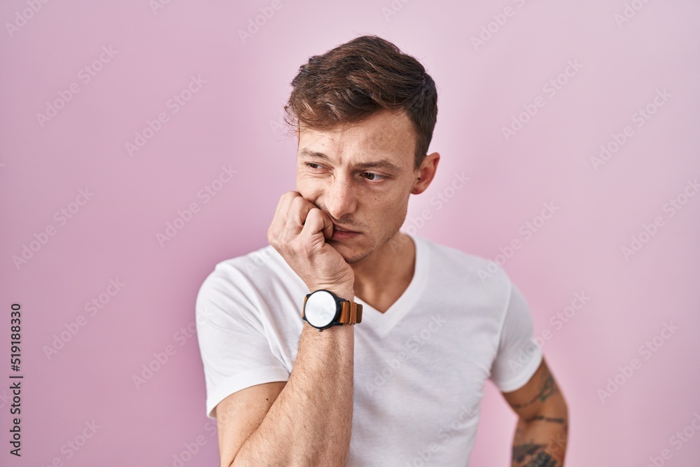 Caucasian man standing over pink background looking stressed and nervous with hands on mouth biting nails. anxiety problem. Caucasian man standing over pink background looking stressed and nervous with hands on mouth biting nails. anxiety problem.