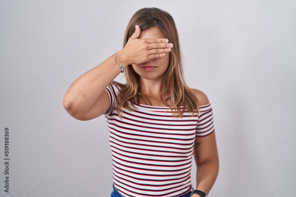 Young hispanic woman standing over isolated background smiling and laughing with hand on face covering eyes for surprise. blind concept. Young hispanic woman standing over isolated background smiling and laughing with hand on face covering eyes for surprise. blind concept.