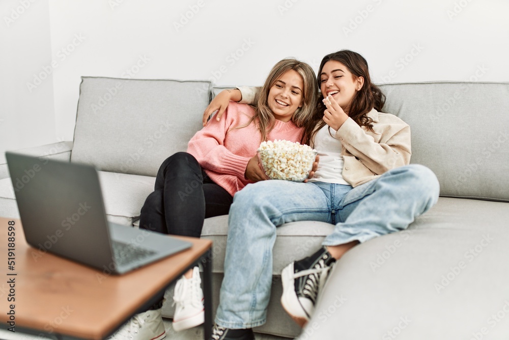Young couple watching film and eating popcorn sitting on the sofa at home.