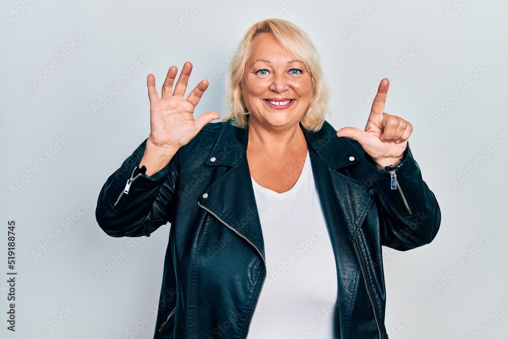 Middle age blonde woman wearing leather jacket showing and pointing up with fingers number seven while smiling confident and happy.