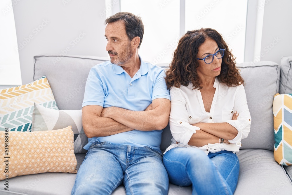 Man and woman couple sitting on sofa with serious expression at home