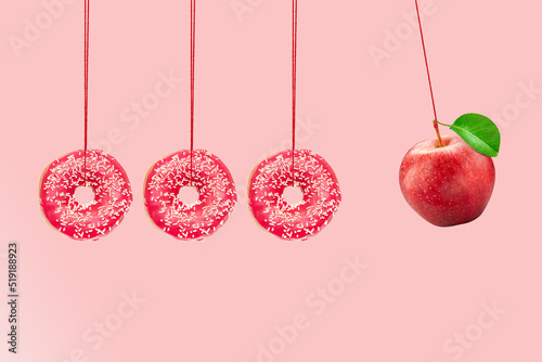 Newton's cradle from doughnuts. Collision balls made from donuts and red apple. Healthy diet concept. Diabetes concept. photo