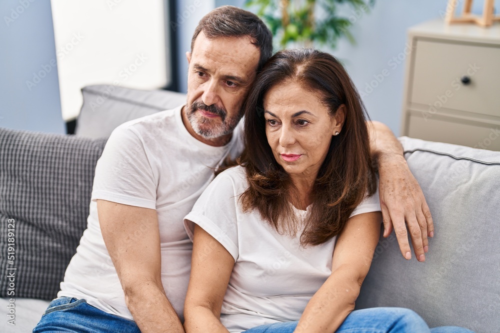 Middle age man and woman couple hugging each other sitting on sofa at home Middle age man and woman couple hugging each other sitting on sofa at home