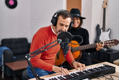 Middle age man and woman musicians playing guitar and keyboard piano singing song at music studio © Krakenimages.com