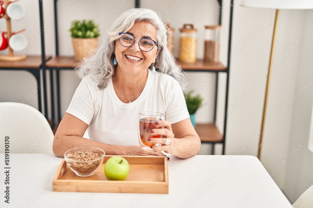 Middle age woman smiling confident having breakfast at home