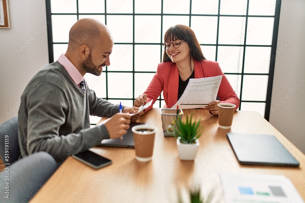 Two hispanic business workers smiling happy working at the office.