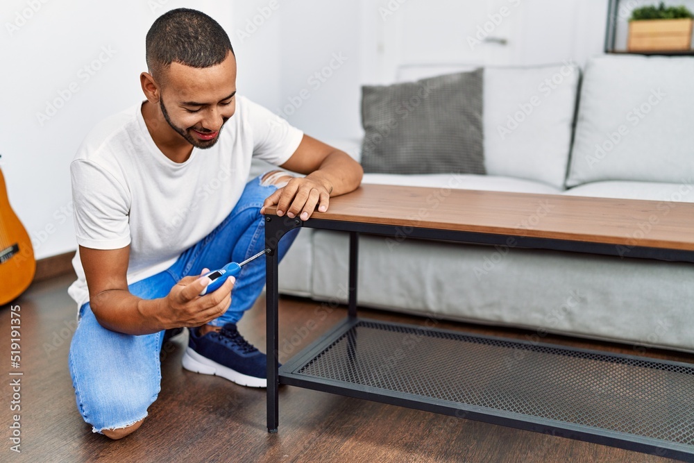 Young hispanic man smiling confident reparing table at home