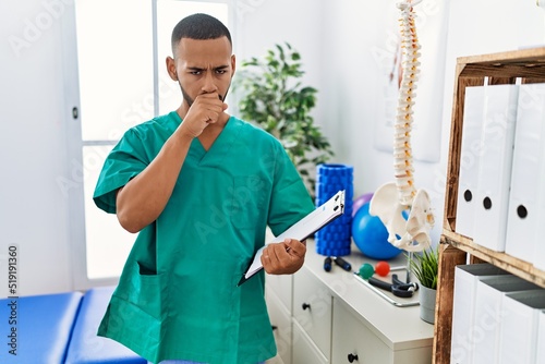 African american physiotherapist man working at pain recovery clinic feeling unwell and coughing as symptom for cold or bronchitis. health care concept.