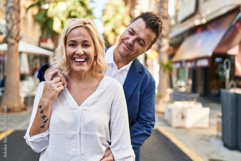 Middle age man and woman couple hugging each other standing at street Middle age man and woman couple hugging each other standing at street