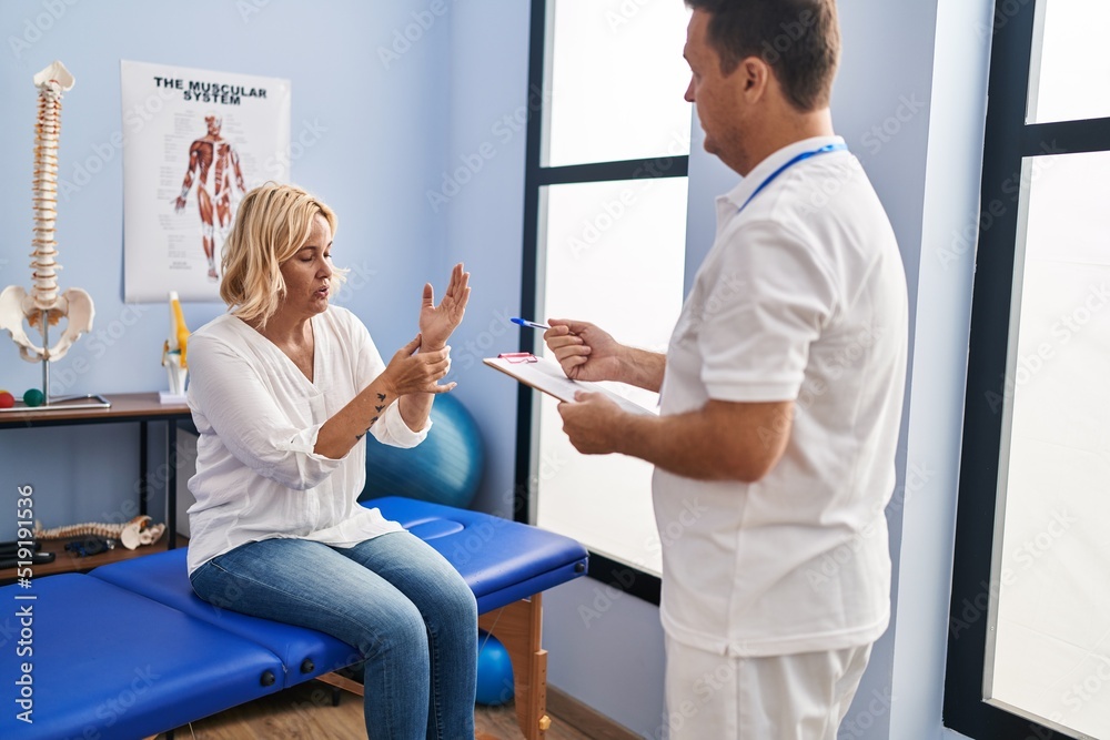 Obraz premium Middle age man and woman physiotherapist and patient having rehab session at physiotherapy clinic