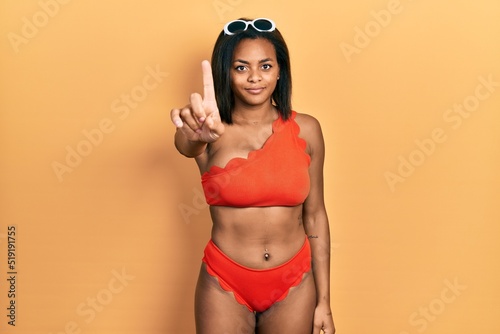 Young african american girl wearing bikini pointing with finger up and angry expression, showing no gesture