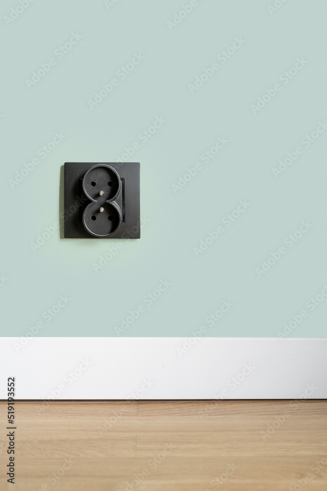 Socket in black plastic frame on green wall Socket in black plastic frame on green wall
